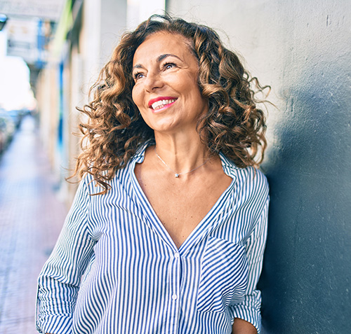 Smiling Middle-aged woman leaning against a wall