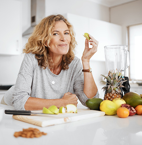 Healthy woman eating fruit in her kitchen